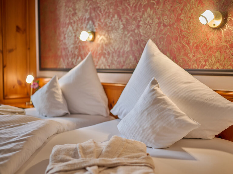 Liebevoll gemachtes Bett mit eleganten Kissen im Hotelzimmer des Hotel Wutzschleife