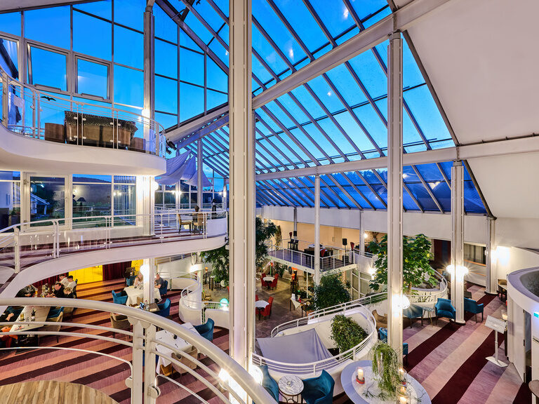 Modernes Hotelfoyer im 4 Sterne Hotel im bayerischen Wald mit Glasdach und architektonisch offenem Design über mehrere Etagen.