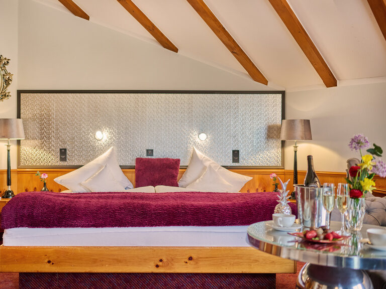 Gemütliches Hotelzimmer mit Doppelbett, Holzbalken und Beleuchtung.