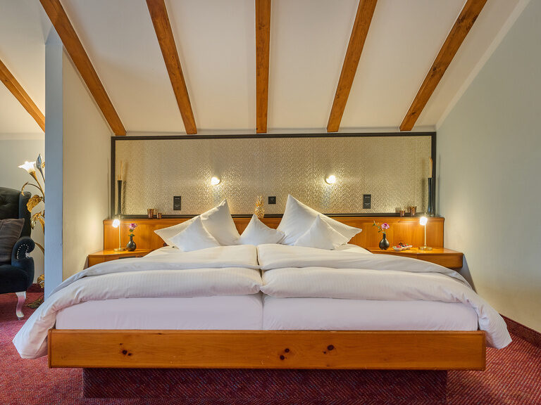 Gemütliches Doppelbett mit Holzrahmen und dekorativen Kissen in stilvoller Hotelsuite.