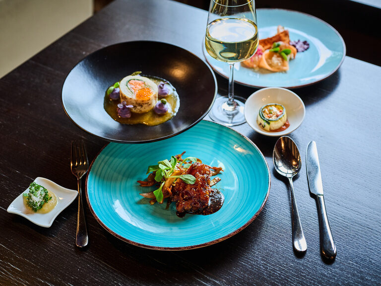 Zwei Personen stoßen mit Cocktails im am Pool des 4 Sterne Hotels im bayerischen Wald an.