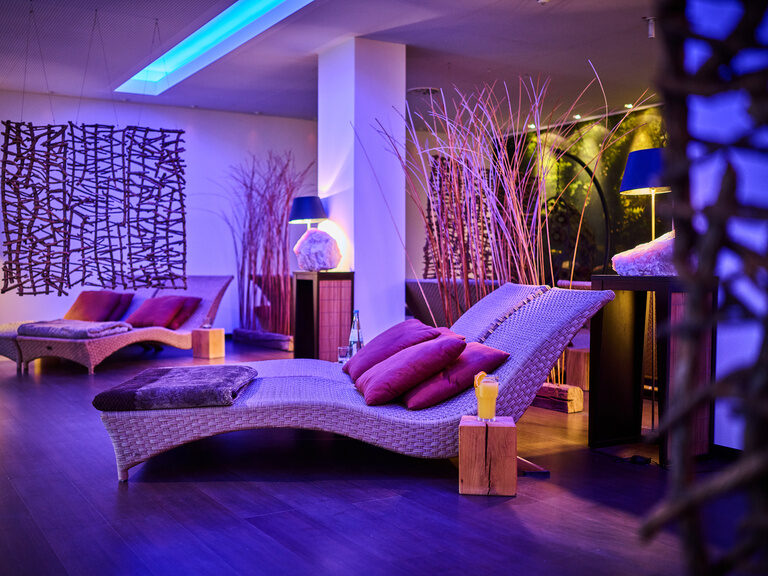 Elegante Ruheliege in Spa-Umgebung mi indirektem, lila Licht.