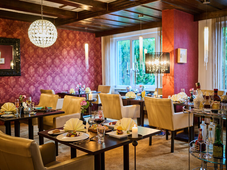 Elegantes Restaurant mit gedeckten Tischen, Kronleuchtern und Barwagen.