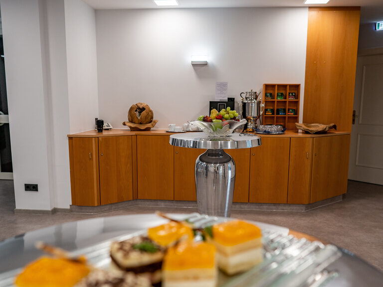 Buffetbereich mit Gebäck, frischem Obst und Getränken auf runden Stehtischen.