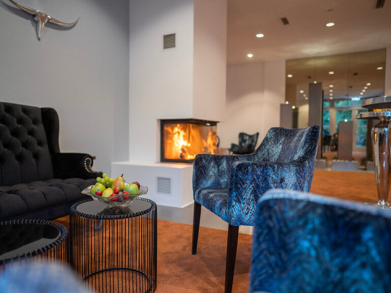 Gemütlicher Loungebereich mit Kaminfeuer, Sofa und frischen Früchten.