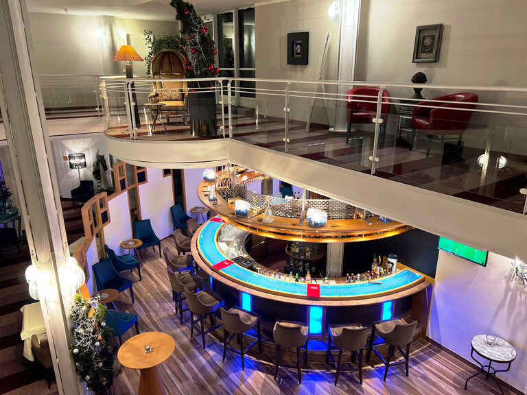 Runde Hotelbar mit blauer LED-Beleuchtung im modernen, zweistöckigen Loungebereich.