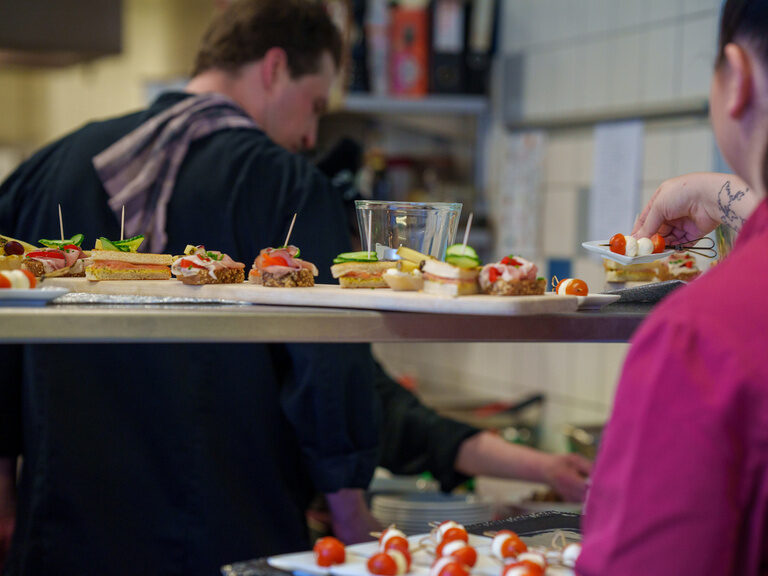 Küchenteam bereitet appetitliche Canapés auf Edelstahltheke zu.