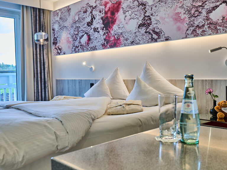 Komfortables Hotelzimmer mit Doppelbett, stilvoller Wandkunst und Getränken.