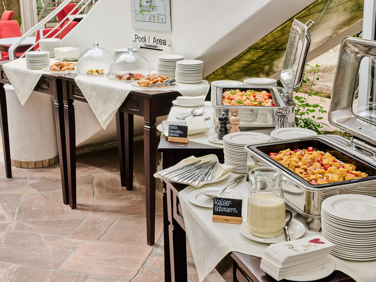 Gesamtsicht auf Buffet mit Kaiserschmarrn, Garnelenpfanne und Frühstücksplatten.