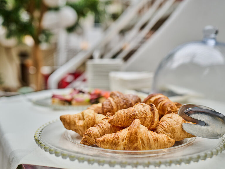 Nahaufnahme von frischen Croissants auf Glasplatte mit Zange.