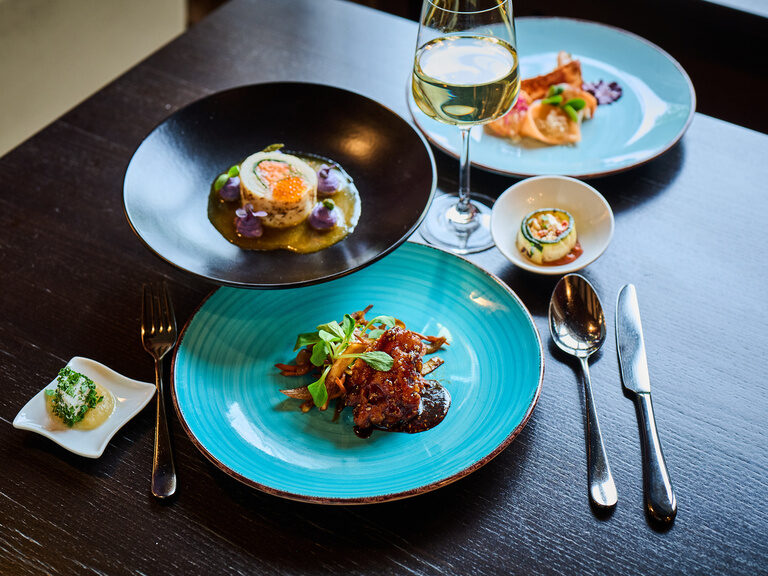 Zwei Personen stoßen mit Cocktails im am Pool des 4 Sterne Hotels im bayerischen Wald an.