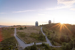 Radarstation bei Sonnenuntergang in Hügellandschaft mit Wanderwegen.