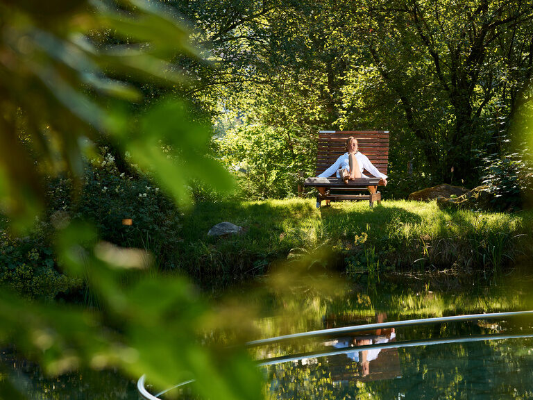 Ein Mann entspannt auf einer Liege in einer grünen Umgebung im Bayerischen Wald