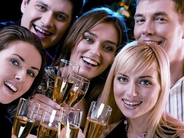 Fünf Freunde feiern und stoßen lächelnd mit Sektgläsern an.