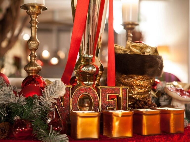 Weihnachtliche Dekoration mit Kerzen, Tannenzweigen und roten Kugeln.